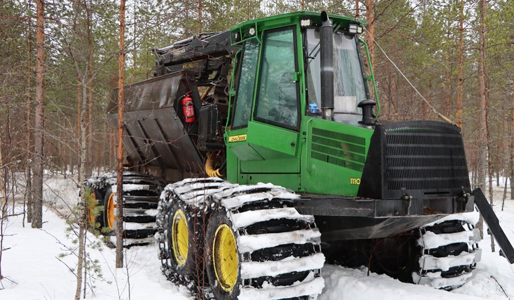 Skogsmaskinen sprider ut aska i skogen på vintern. 