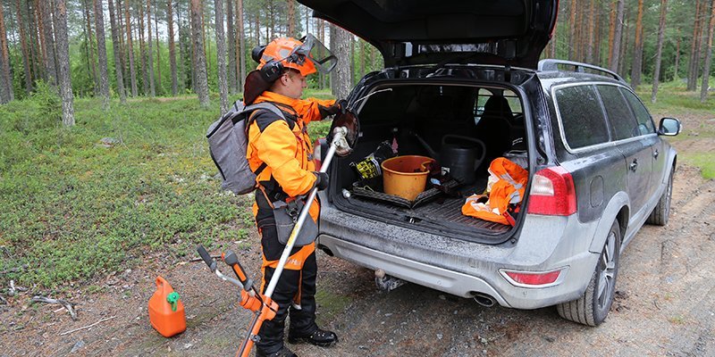 Sakari Mantila packar sina arbetsredskap i bilens baklucka vid skogsbilvägen.