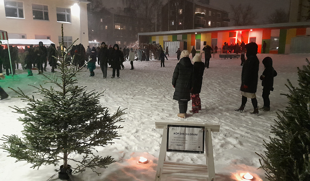 Människor på vintern på en julmarknad. I förgrunden syns Kurk Fields & Forets julgranar och brinnande facklor.