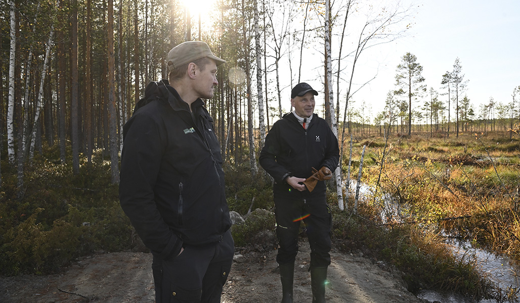 Ville Koukkari och Jari Järvenpää står vid kanten av våtmarken, där skyddsområdet börjar. 