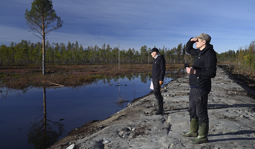 Ville Koukkari och Jari Järvenpää står på våtmarkens vall och tittar ut mot landskapet.